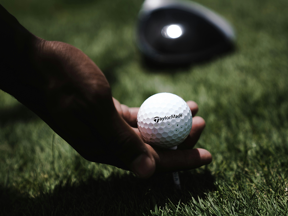 Golfer laying golf ball on green
